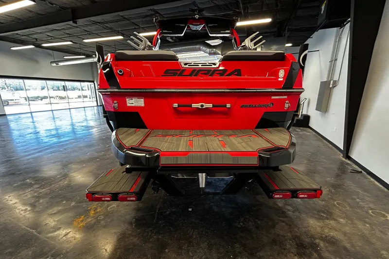 Slide: The Image of 2025 Supra SL boat in showroom, rear view with red and black design. - 3
