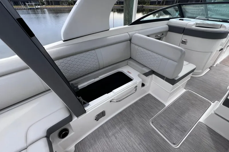 Slide: The Image of 2020 Sea Ray SDX 270 Outboard interior with open storage compartment and cushioned seating. - 24