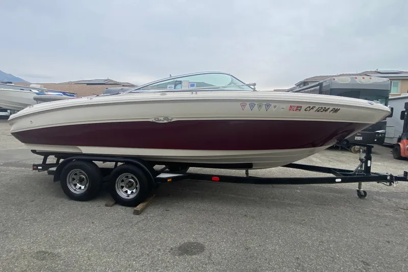 The Image of 2000 Sea Ray 210 Bow Rider boat on trailer, parked outdoors. - 1