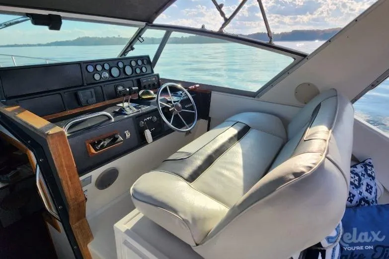 Slide: The Image of 1988 Sea Ray 390 Express Cruiser helm with leather seat and scenic water view. - 10