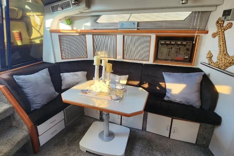 Slide: The Image of 1988 Sea Ray 390 Express Cruiser interior with cozy seating, table, and nautical decor. - 19