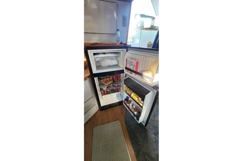 Slide: The Image of Open refrigerator inside 1988 Sea Ray 390 Express Cruiser, stocked with food and drinks. - 23