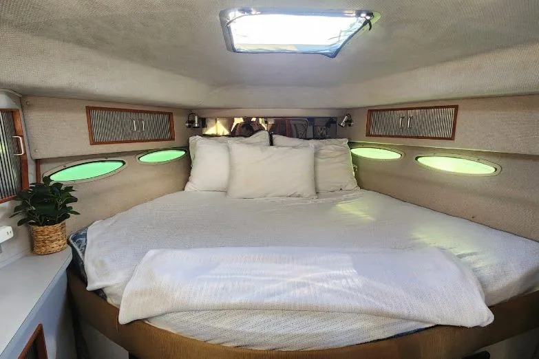 Slide: The Image of Cozy cabin interior of 1988 Sea Ray 390 Express Cruiser with skylight and plush bedding. - 29
