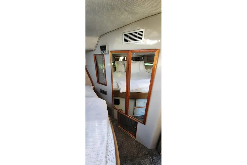 Slide: The Image of 1988 Sea Ray 390 Express Cruiser cabin interior with mirrored closet and cozy bedding. - 31