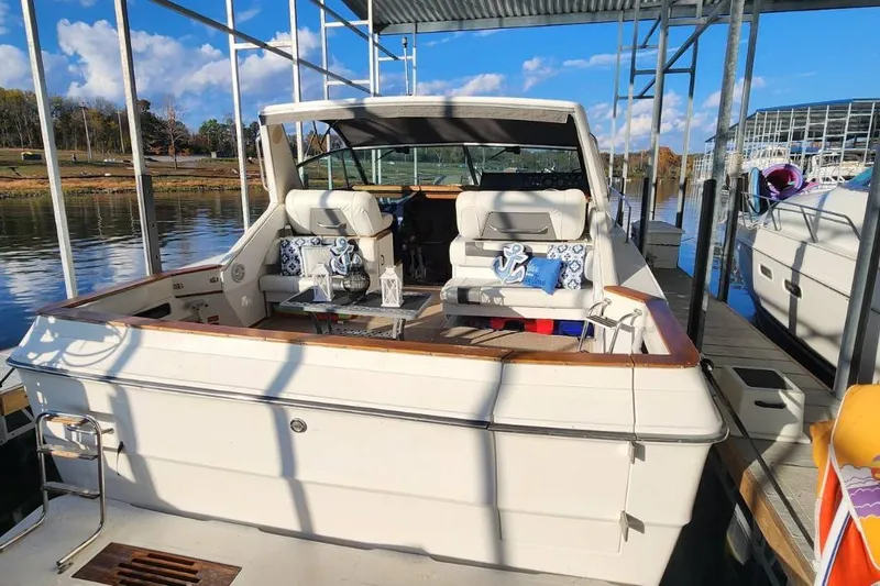 Slide: The Image of 1988 Sea Ray 390 Express Cruiser docked, featuring a spacious seating area with nautical decor. - 4