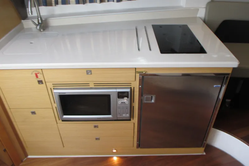 Slide: The Image of Compact kitchen area in 2013 Pursuit SC 365i Sport Coupe with microwave and stainless steel fridge. - 26