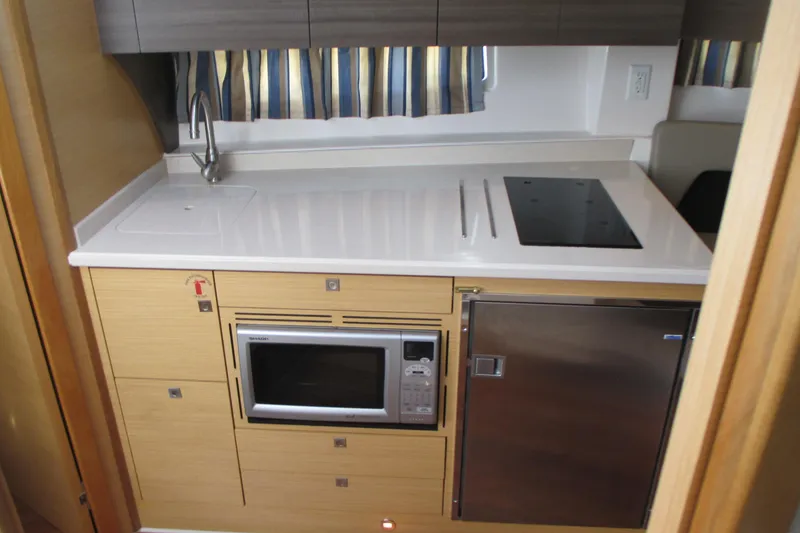 Slide: The Image of Compact kitchen in 2013 Pursuit SC 365i Sport Coupe with sink, stove, microwave, and fridge. - 27