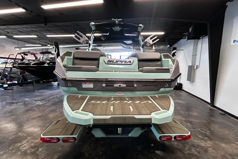 Slide: The Image of 2025 Supra SA boat in showroom, rear view with seating and deck. - 3