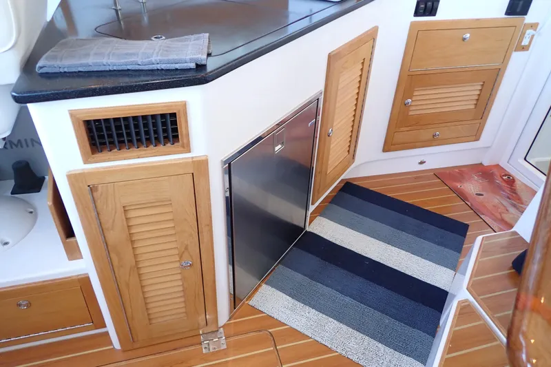 Slide: The Image of Interior of 2023 True North 34 Outboard Express with wood cabinetry and striped rug. - 15