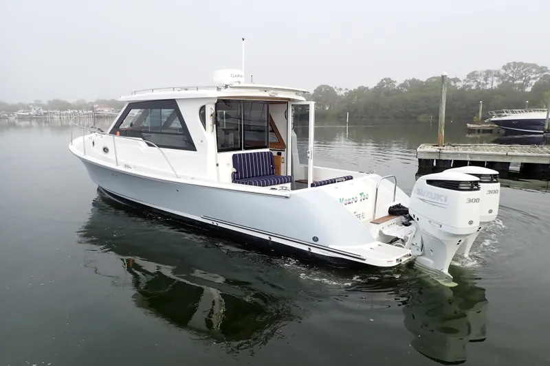 Slide: The Image of 2023 True North 34 Outboard Express boat on calm water, featuring dual Suzuki engines. - 155