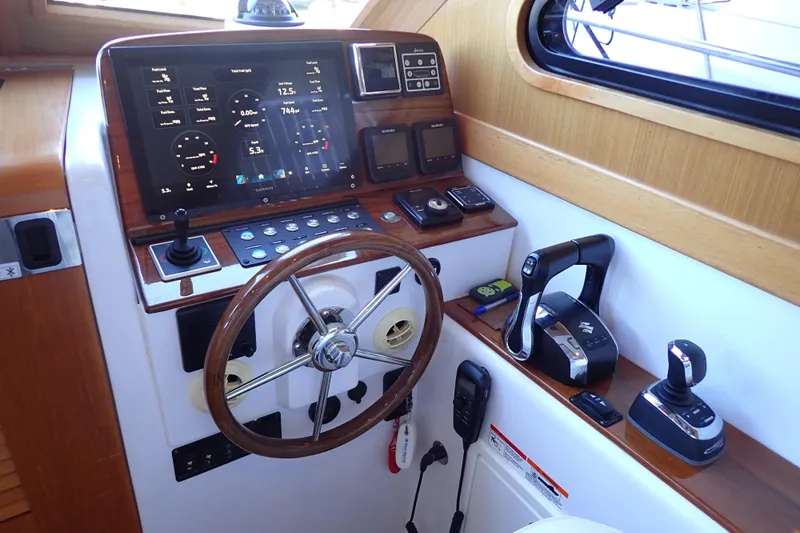 Slide: The Image of 2023 True North 34 Outboard Express helm with advanced navigation controls and wooden accents. - 17