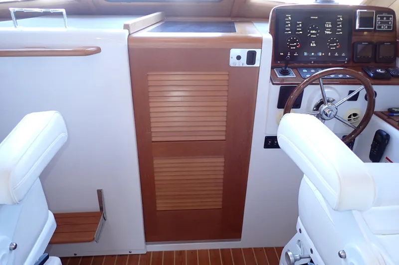 Slide: The Image of 2023 True North 34 Outboard Express helm with wooden accents and modern controls. - 19