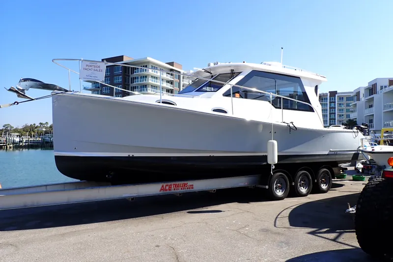 Slide: The Image of 2023 True North 34 Outboard Express boat on trailer near waterfront buildings. - 2