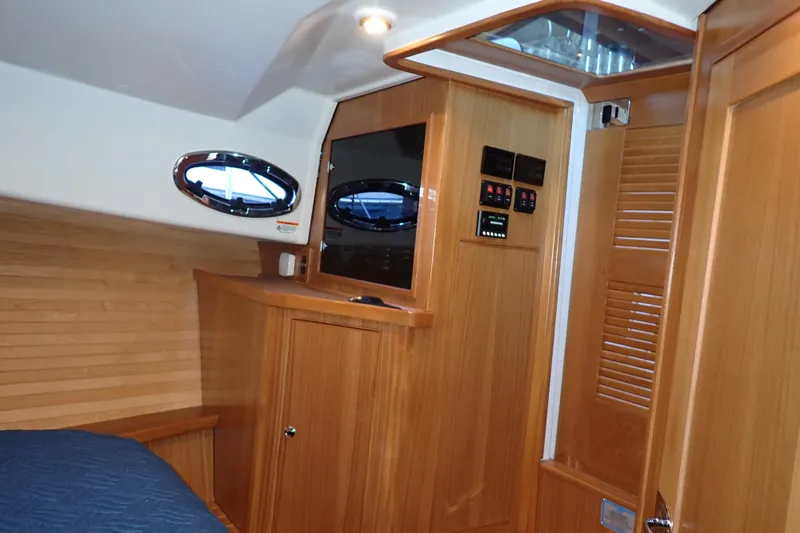 Slide: The Image of 2023 True North 34 Outboard Express cabin interior with wood paneling and porthole window. - 21