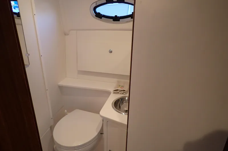 Slide: The Image of Compact bathroom in 2023 True North 34 Outboard Express boat, featuring toilet and sink. - 23
