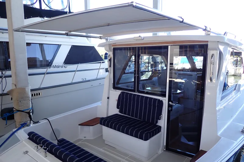 Slide: The Image of 2023 True North 34 Outboard Express boat with striped seating and canopy at dock. - 41