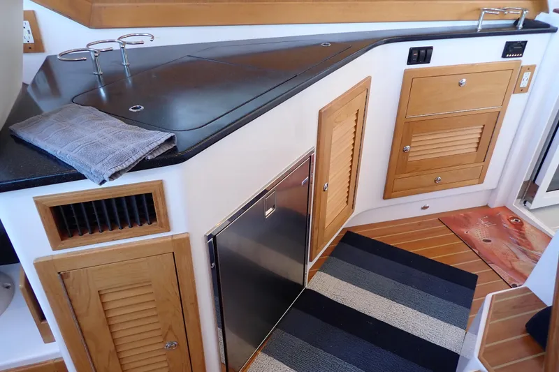 Slide: The Image of 2023 True North 34 Outboard Express interior with wooden cabinetry and modern appliances. - 43
