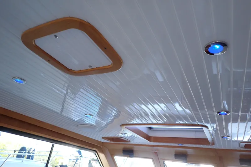 Slide: The Image of Interior ceiling of 2023 True North 34 Outboard Express with modern lighting and wood accents. - 63
