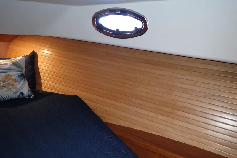 Slide: The Image of 2023 True North 34 Outboard Express cabin with wood paneling and porthole window. - 66