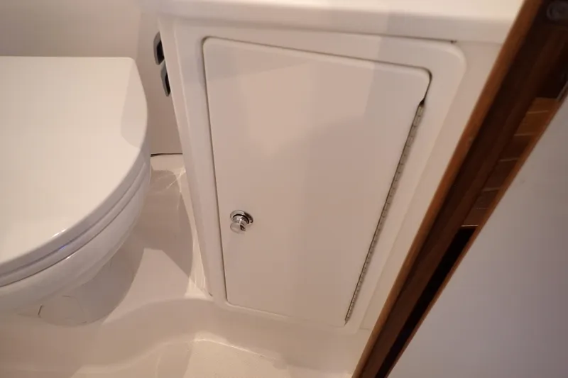 Slide: The Image of 2023 True North 34 Outboard Express bathroom with white toilet and storage cabinet. - 80