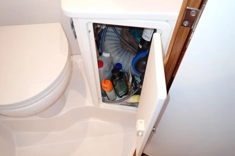 Slide: The Image of 2023 True North 34 Outboard Express bathroom storage with open cabinet and supplies. - 81