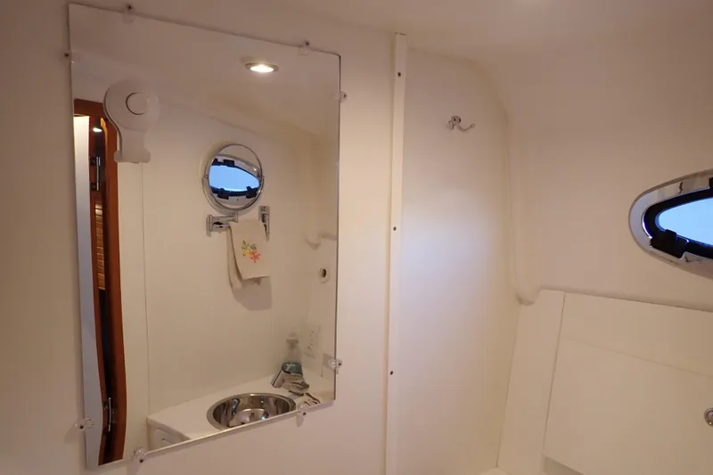 Slide: The Image of Bathroom interior of 2023 True North 34 Outboard Express yacht, featuring mirror and porthole. - 82