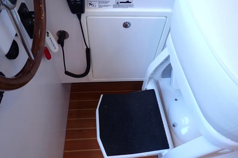 Slide: The Image of 2023 True North 34 Outboard Express helm area with wooden steering wheel and black footrest. - 85