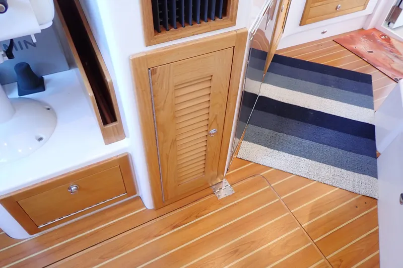 Slide: The Image of 2023 True North 34 Outboard Express interior with wood flooring and striped rug. - 91