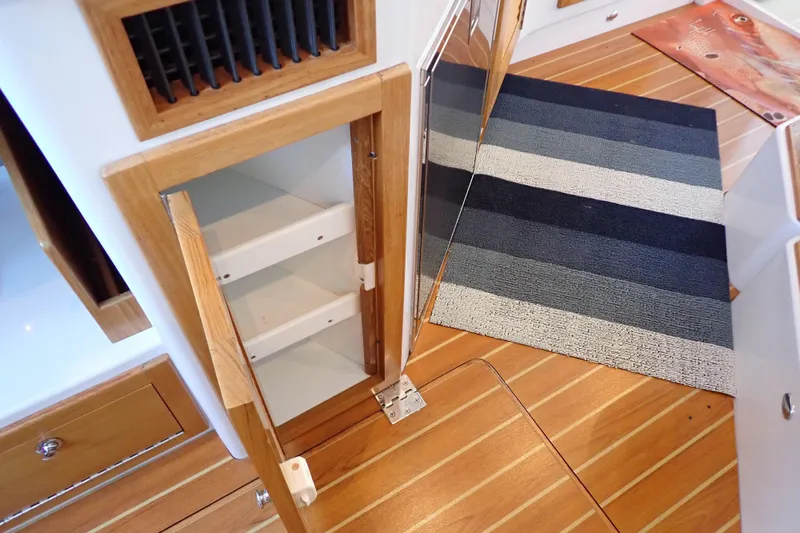 Slide: The Image of Interior of 2023 True North 34 Outboard Express with open wooden cabinet and striped rug. - 92
