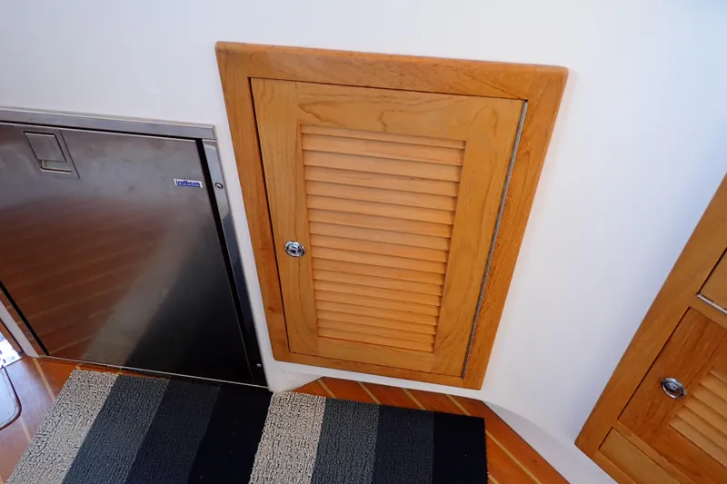 Slide: The Image of Wooden cabinet and stainless steel fridge in 2023 True North 34 Outboard Express boat interior. - 93