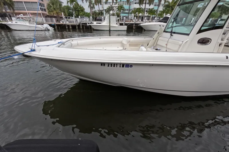 Slide: The Image of 2013 Boston Whaler 320 Outrage docked near waterfront buildings and palm trees. - 35