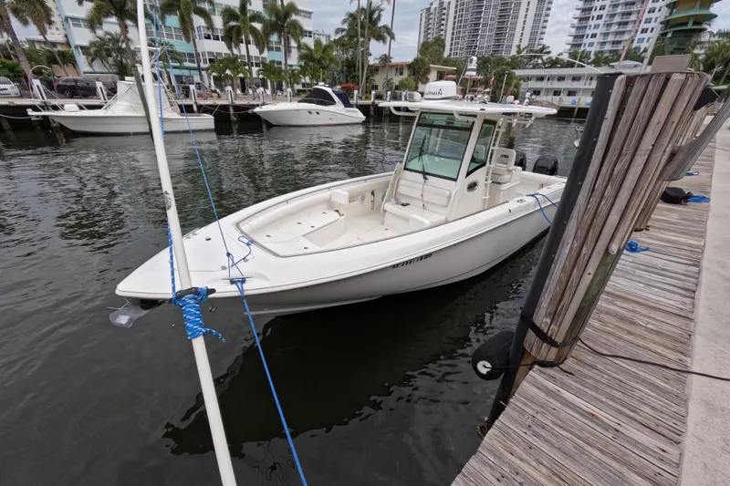 Slide: The Image of 2013 Boston Whaler 320 Outrage docked at marina with modern buildings in background. - 36