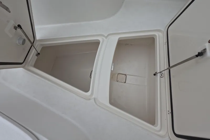 Slide: The Image of 2013 Boston Whaler 320 Outrage boat interior with open storage compartment, docked by the water. - 53