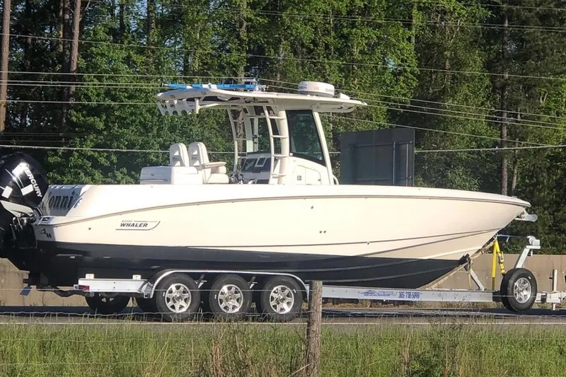 Slide: The Image of 2013 Boston Whaler 320 Outrage boat on trailer, surrounded by trees. - 55