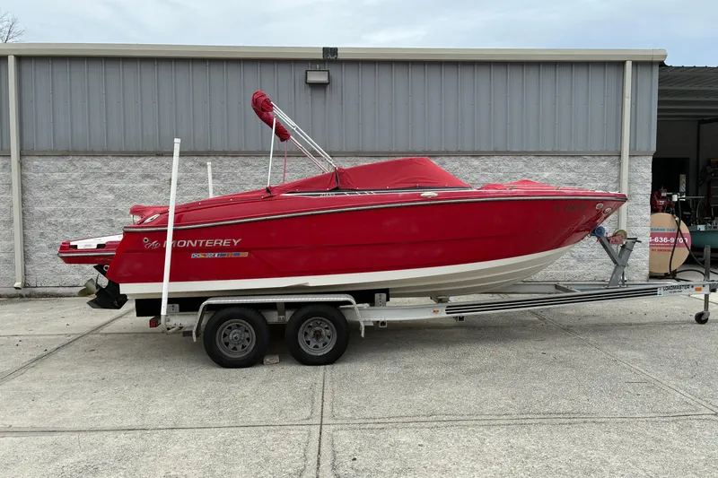 Slide: The Image of Red 2013 Monterey 214SS Super Sport boat on trailer, parked outside a building. - 2
