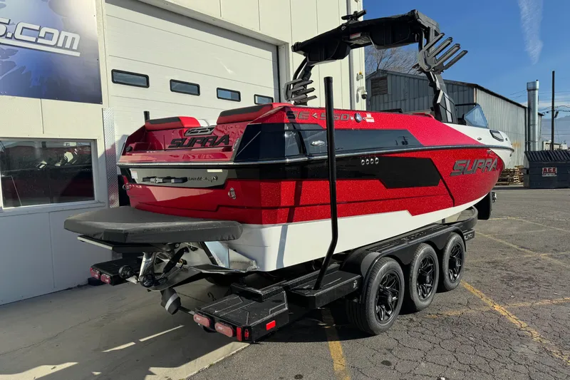 Slide: The Image of 2026 Supra SE 575 boat on trailer, red and black design, parked outside a building. - 4