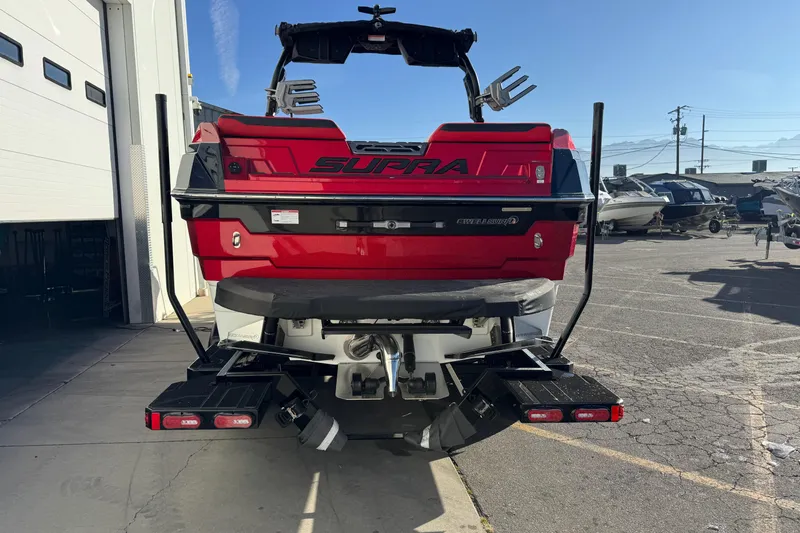 Slide: The Image of 2026 Supra SE 575 boat, red and black, rear view in a marina setting. - 5