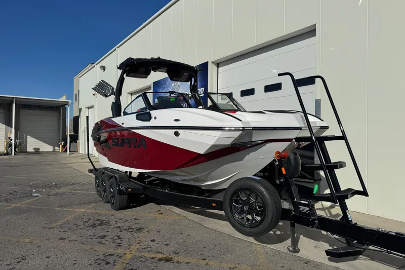 Slide: The Image of 2026 Supra SE 575 boat on trailer outside a garage, featuring sleek design and modern features. - 6