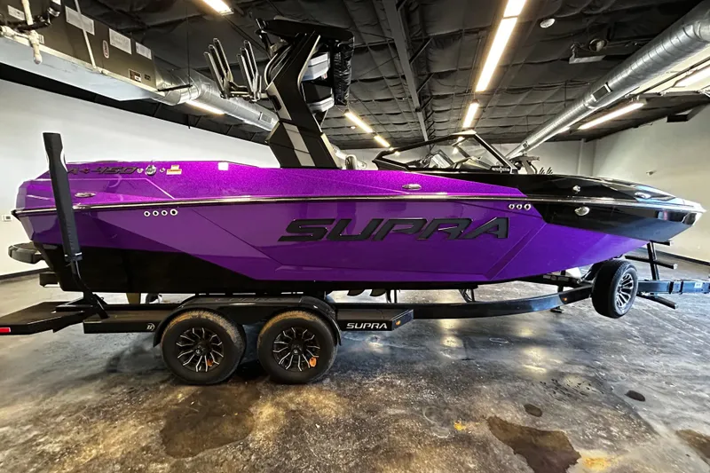 Slide: The Image of 2025 Supra SA boat in vibrant purple on a trailer, displayed indoors. - 2