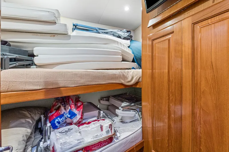 Slide: The Image of Storage area in 1998 Viking 72 Enclosed Bridge yacht with stacked supplies and wooden cabinetry. - 21