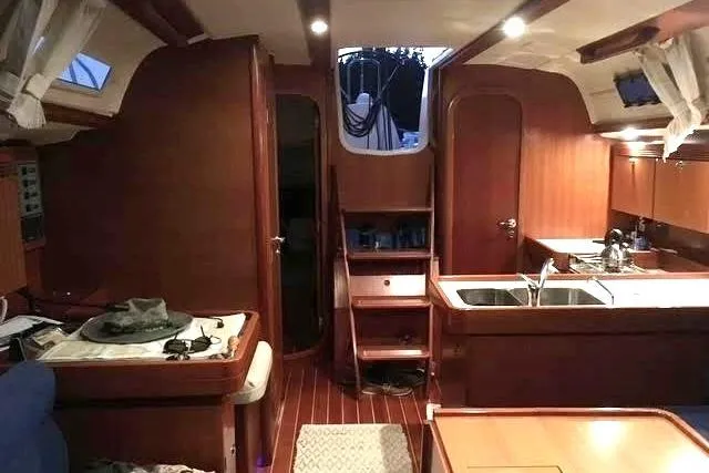 Slide: The Image of Interior of 2004 Dufour 40 Performance yacht, featuring wood finishes and a compact kitchen area. - 5