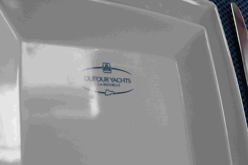 Slide: The Image of White plate with Dufour Yachts logo, La Rochelle, on a yacht dining setting. - 53
