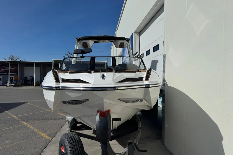 Slide: The Image of 2026 Supra SL 575 boat on trailer, parked outside a building under clear blue sky. - 5