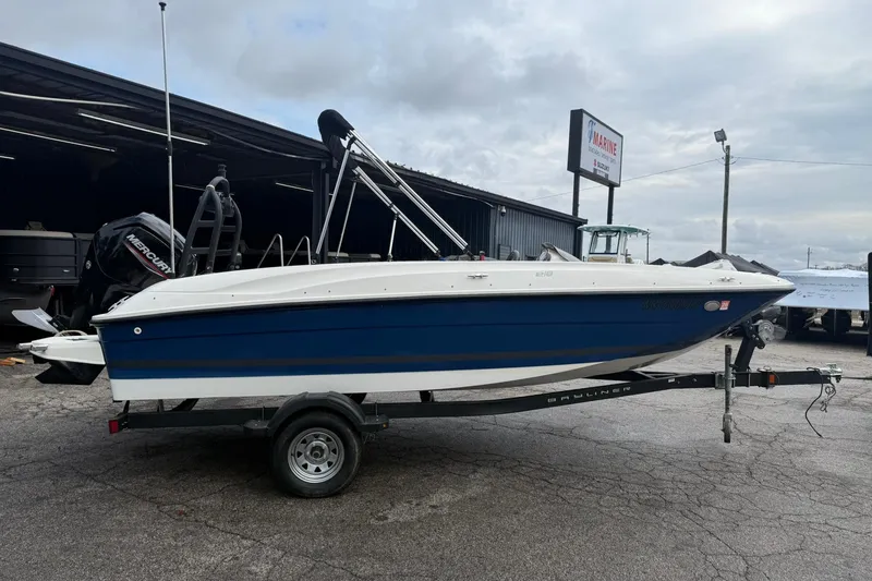 Slide: The Image of 2021 Bayliner Element E18 boat on trailer, parked outdoors near a marine shop. - 3