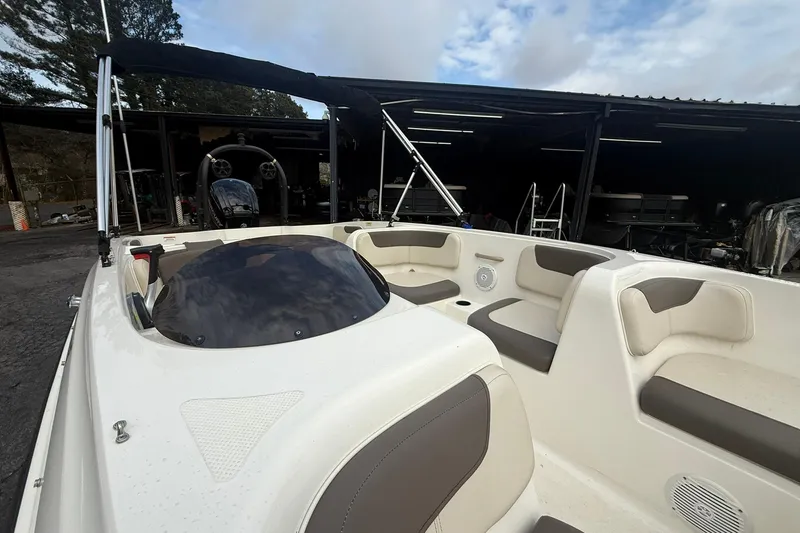 Slide: The Image of 2021 Bayliner Element E18 boat interior with seating and steering wheel, parked in a marina. - 8
