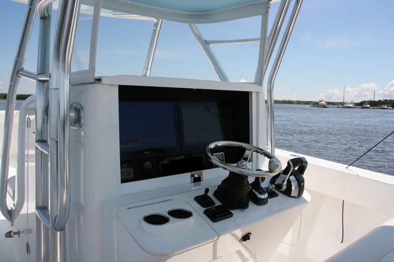 Slide: The Image of 2019 Bahama 41 boat helm with steering wheel and navigation screens on a sunny day. - 21