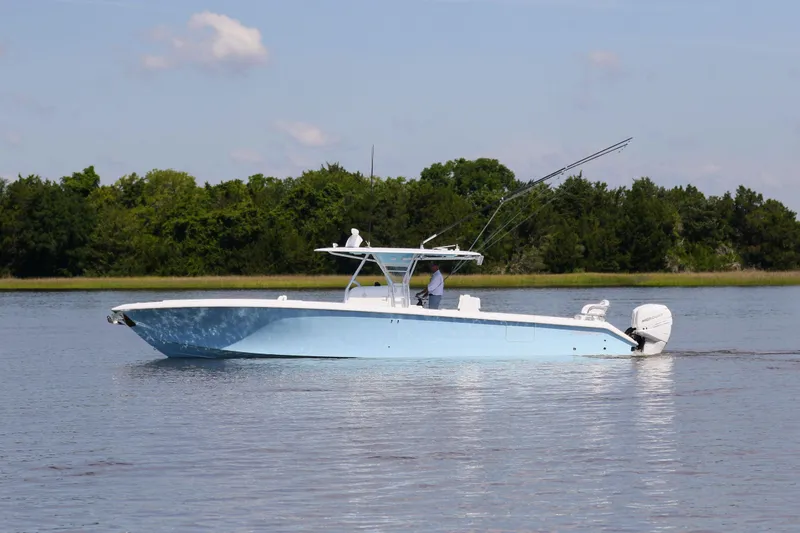 Slide: The Image of 2019 Bahama 41 boat cruising on calm water with lush green trees in the background. - 5