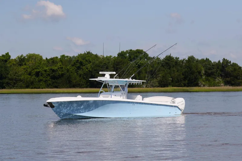 Slide: The Image of 2019 Bahama 41 boat on calm water with fishing rods, lush green background. - 6