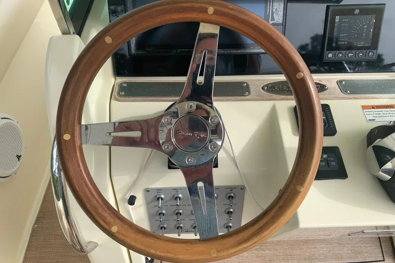Slide: The Image of Steering wheel of 2019 Chris-Craft Catalina 27 boat, featuring wood and chrome design. - 32