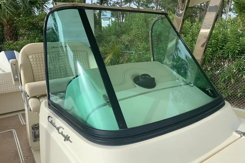 Slide: The Image of 2019 Chris-Craft Catalina 27 boat helm with windshield and seating, surrounded by greenery. - 45